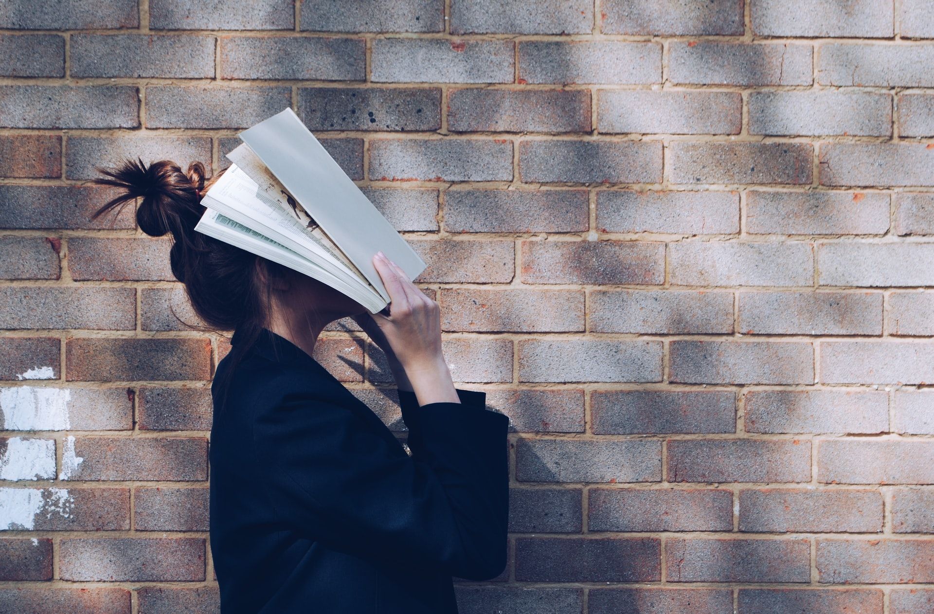 A woman covering her face with a book.