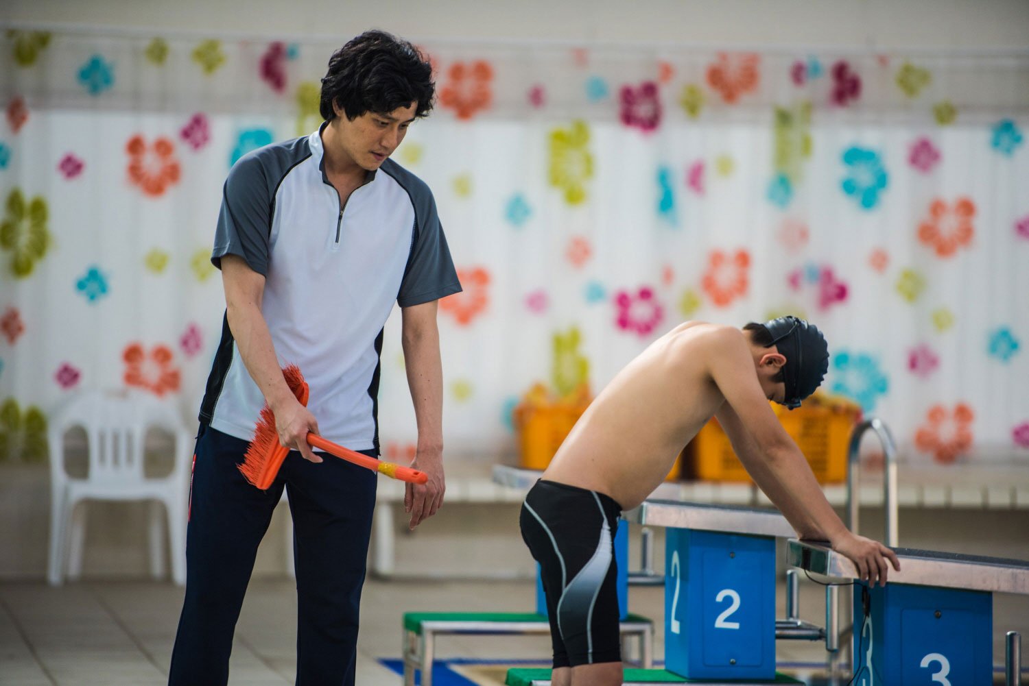 Scene from the film Fourth Place in which a swimming coach is hitting a boy with a broom.